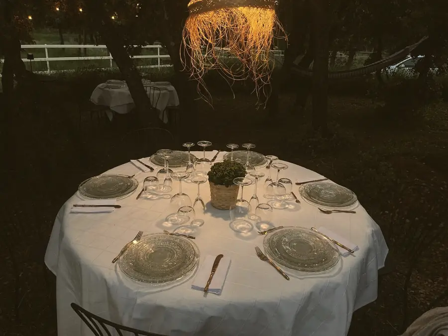 A table set under the holm oaks at dusk